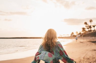 Mutlu, güzel bir kadın kumsalda yürüyor ve gün batımında eğleniyor. Tatillerde boş zaman, özgürlük kavramı