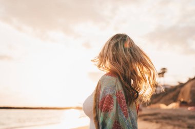 Sahilde denize bakan genç bir kadının portresi. Boş zamanın ve dışarıda özgürlüğün tadını çıkarıyor. Rahatlamak ve hareketli sarı saçlar..