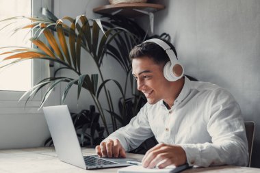 Mutlu iş adamı kulaklık takıyor ve dizüstü bilgisayar kullanıyor, pistin tadını çıkarıyor, müzik dinliyor.