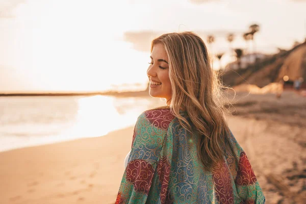 happy blonde woman at beach, sunset sky and blurred sea on background