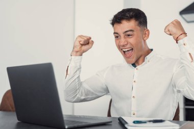 Masada oturan adam dizüstü bilgisayardaki e-postaları okuyunca mutlu oluyor. Erkek girişimci harika iş haberleri alır, kariyer gelişimini kutlar, ilerler. Başarı, kazanma, açık artırma zafer konsepti