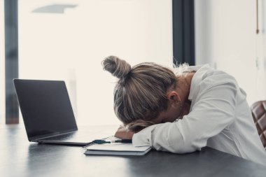 Yorgun, genç, Kafkasyalı bayan çalışan çalışma masasında fazla mesai raporunu hazırlıyor. Yorgun bir kadın iş yerinde uyuyakalıyor, geç saate kadar çalışıyor. Yorgunluk, yorgunluk konsepti.