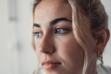 Ciddi düşünceli, güzel, beyaz, yetişkin bir kızın yüz portresi. Güzel sarışın bir kadının yüzü pürüzsüz tenli, uzun kirpikleri var. Başka tarafa bakıyor, düşünüyor, hayal ediyor, güzellik bakımını teşvik ediyor.