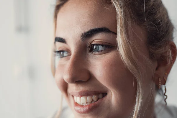 Cropped close up part of female face, happy young Caucasian woman portrait look aside, having white-toothed smile, wrinkles around eyes, staring into distance. Natural beauty, skincare treatments ad