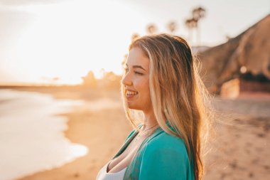 Sahilde denize bakan genç bir kadının portresi. Boş zamanın ve dışarıda özgürlüğün tadını çıkarıyor. Rahatlamak ve mutlu anlar yaşamak..