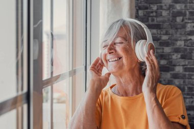 Mutlu, olgun, emekli, kulaklıkla popüler müzik dinleyen, yalnız görünen bir düşünce penceresi olan, evde yalnız başına huzurlu ve tasasız hafta sonunun keyfini çıkaran, stresten uzak boş zaman eğlencesi olan yaşlı kadın..