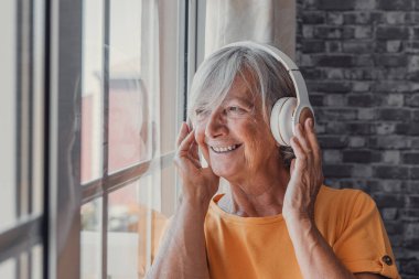 Mutlu, olgun, emekli, kulaklıkla popüler müzik dinleyen, yalnız görünen bir düşünce penceresi olan, evde yalnız başına huzurlu ve tasasız hafta sonunun keyfini çıkaran, stresten uzak boş zaman eğlencesi olan yaşlı kadın..