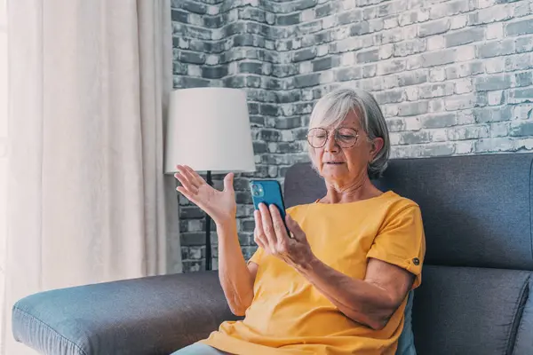 Shocked upset elderly woman getting bad news, finding fraud, money stealing, loss, overspending, financial problem, holding calculator, using phone, staring at monitor