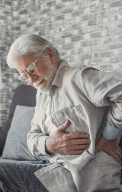 Upset senior elder man feel sudden back pain muscles ache tension injury sitting at home, sad old grandfather touching spine having lower lumbago backache osteoarthritis arthritis, backache concept
