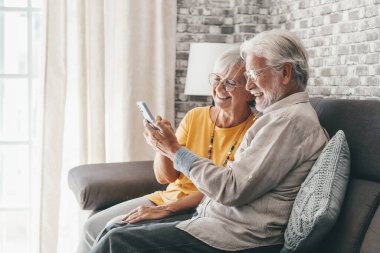 Yaşlı büyükbaba ve büyükanne akıllı telefon uygulamaları, orta yaşlı eş çevrimiçi eğlencelerden, eski koca, eski nesil ve modern teknoloji konseptiyle selfie çekmekten zevk alarak zaman geçiriyorlar.
