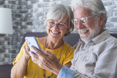 Yaşlı büyükbaba ve büyükanne akıllı telefon uygulamaları, orta yaşlı eş çevrimiçi eğlencelerden, eski koca, eski nesil ve modern teknoloji konseptiyle selfie çekmekten zevk alarak zaman geçiriyorlar.
