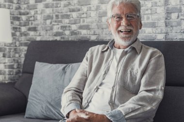 Mutlu 80 'lerin erkek portresi kanepede oturur hafta sonu rahatlayan kameraya bakar, 70' lerin büyük dedesi gülümser evde ya da huzurevinde kanepede dinlenir, iyimserliğini gösterir.
