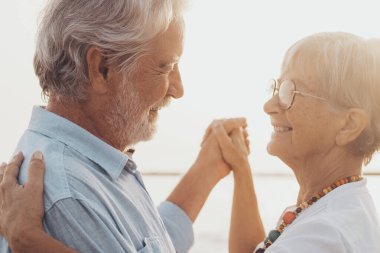 Bir çift olgun insan birlikte dans ediyor ve kumsalda kumsalda eğleniyor ve anın tadını çıkarıyor. Yaşlıların birbirine aşık portresi. Birbirlerine bakıp eğleniyorlar..