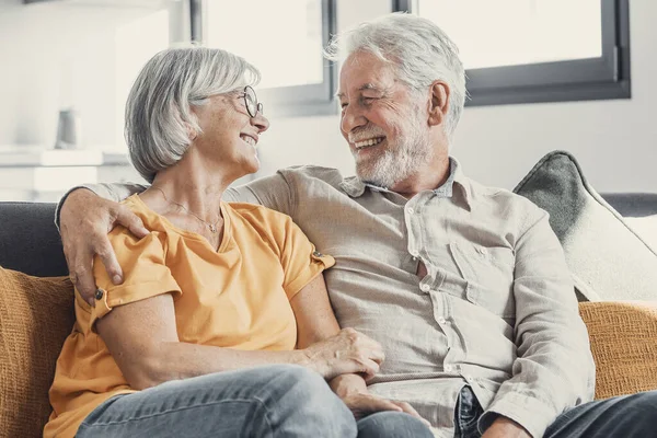 Happy laughing older married couple talking, laughing, standing in home interior together, hugging with love, enjoying close relationships, trust, support, care, feeling joy, tenderness