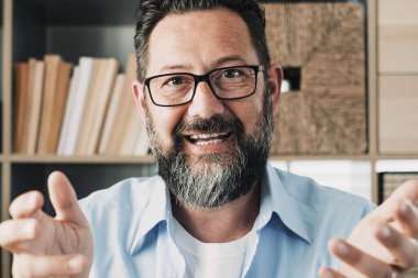 Kafa portresi, kendine güvenen iş adamı koçu kameraya bakıyor ve konuşuyor, hoca hoparlörü çevrimiçi ders veriyor, modern dolapta ahşap çalışma masasında oturuyor, açıklama yapıyor.
