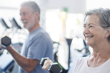 Spor salonunda iki son sınıf öğrencisi ellerinde dambıllarla antrenman yapıyor. Sağlıklı ve sağlıklı bir yaşam tarzı. Antrenman ve ağırlık kaldırma.