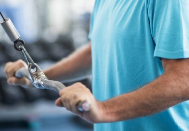 Olgun bir adam spor salonunda bir makineyle ağırlık kaldırıyor - aktif son sınıf eğitimi tek başına - sağlıklı ve fitness adamı