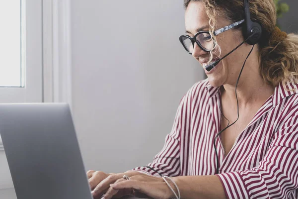 Attractive caucasian woman sit at home office room wearing headset take part in educational webinar using laptop. Video call event with clients or personal chat with friend remotely concept