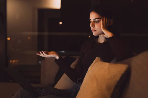 Unhappy young female worker look at laptop screen shocked by gadget breakdown or operational problems at late night. Frustrated woman confused surprised by unexpected error on computer device.