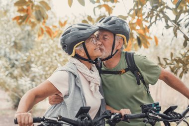 Birbirine aşık iki tatlı son sınıf öğrencisi dışarıda motosikletlerle eğleniyor. Yaşlı adam karısını öpüyor ve gülümsüyor..