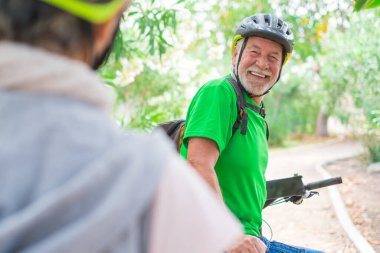 Bahar parkında kucaklaşan yaşlı çift birlikte eğleniyor ve ağaçlara bakıyor. Birbirini seven iki yaşlı ve olgun insan..