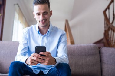 Heyecan gülen adam telefon ekranına bakarak, mobil uygulama kullanarak, sosyal ağda mesaj yazarak, haber okuma, e-posta, arkadaşlarınızla sohbet erkek öğrenci, oyun oynarken, komik video izlerken
