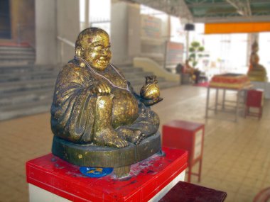 Gülümseyen Buda heykeli beyaz arka planda altın yaprağıyla kaplanmış.