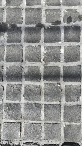 Görüntü desenli, şebeke desenli gri kaldırımları, eşsiz yüzey detaylarını ve gölgelerini gösteren bir görüntüdür.