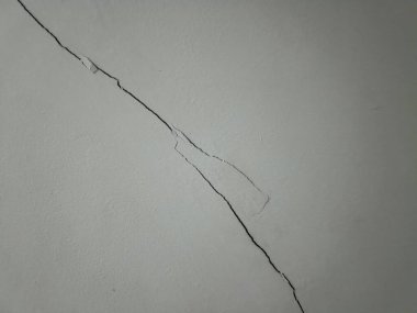 Çatlamış bir duvar yüzeyinde hasar ve yıpranma izleri görülüyor. Ev ortamında onarım ve bakım gereksinimleri vurgulanıyor.