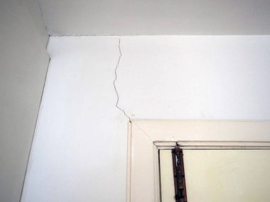 Odadaki çatlak duvarda hasar ve yıpranma izleri var. Yapısal sorunları vurguluyor ve onarılması gerekiyor.