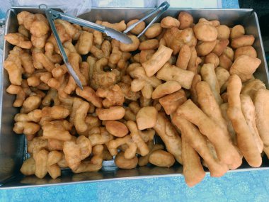 Lezzetli, bol yağda kızartılmış hamur çubukları güzelce tepsiye konur ve tadını çıkarmaya hazırdır. Lezzetli ikram neşe dolu bir beklenti hissi verir.