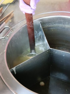 Sokak yemeği hazırlıkları sırasında büyük tencerede sıcak çorba karıştırmak. Mutfak sürecine ve hazır yemeğin sıcaklığına odaklanmış. Aşçılığa adanmışlık ve basit işçilik.