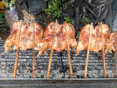 Üç ızgara tavuk kömür ızgarasında pişiyor, lezzetli ve lezzetli görünüyor, lezzetli bir yemek için hazır.