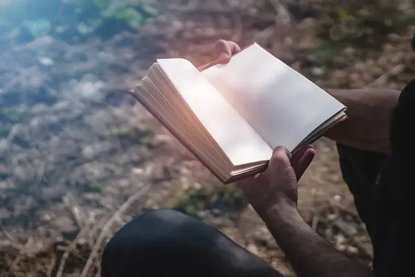 Açık havada kitap okuyan bir adam. Erkek, iki eliyle boş bir kitap tutuyor, rahip İncil okuyor ya da doğada okuyan bir öğrenci. Yan görünüm, metin için boşluk kopyala, kitaba odaklan.