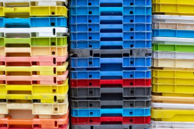 Arka plan, doku ya da kaplama olarak kullanılabilecek çok renkli plastik balıkçı sandıkları yığınını kapat