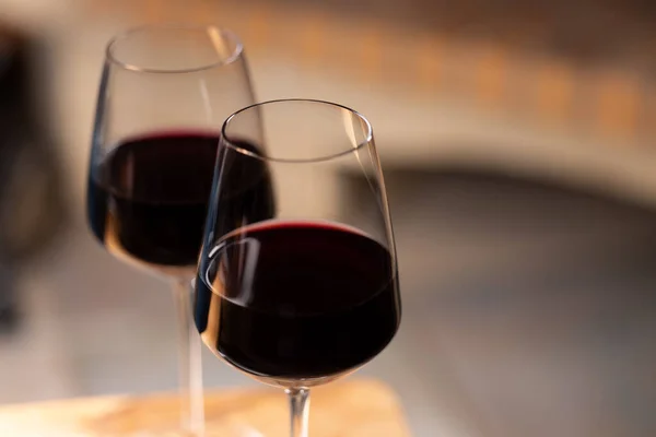 Stock image two glasses of red wine placed on a table with a fireplace in the background. Reflection of glasses on the table. Concept of conviviality at aperitif time