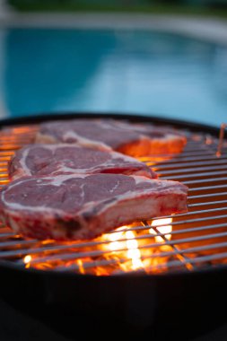 Tente, arka planda yüzme havuzu olan barbeküde ızgara et. Tatil ve rahatlama sembolü