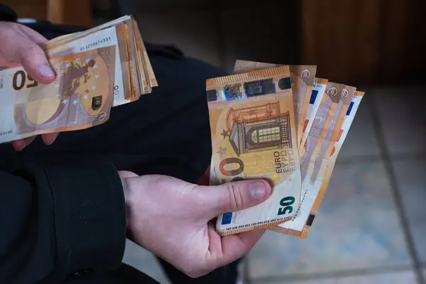 Ödeme yapmak için 50 Euro 'luk banknotları tutan el kameraları.