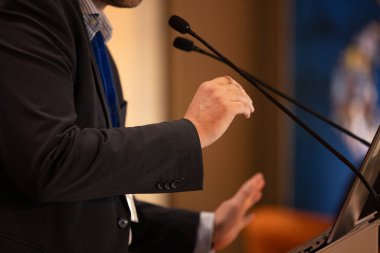 Politik bir miting, sempozyum veya toplantı sırasında kürsüden konuşma yapan bir mikrofona ve bir hoparlörün ellerine odaklanın.