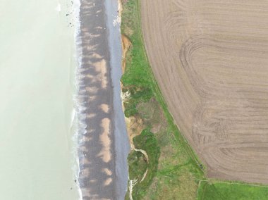 Normandiya 'daki uçurumları, çakıl taşlarını ve denizi gösteren bir insansız hava aracı tarafından çekilen hava görüntüsü.