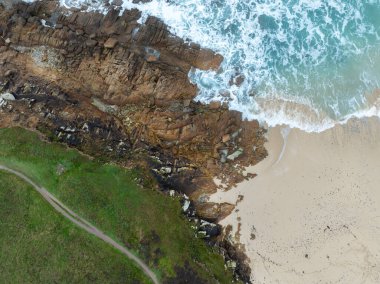 Denizi ve kumsalda dalgaları gösteren bir hava aracıyla çekilmiş hava görüntüsü.