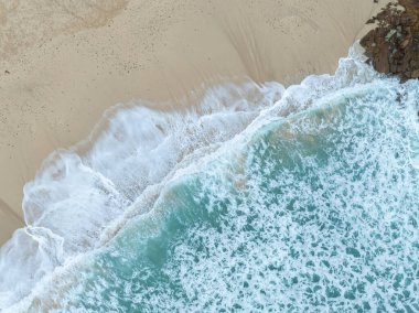 Denizi ve kumsalda dalgaları gösteren bir hava aracıyla çekilmiş hava görüntüsü.