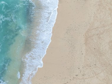 Denizi ve kumsalda dalgaları gösteren bir hava aracıyla çekilmiş hava görüntüsü.