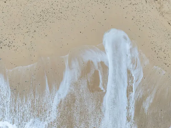 Denizi ve kumsalda dalgaları gösteren bir hava aracıyla çekilmiş hava görüntüsü.