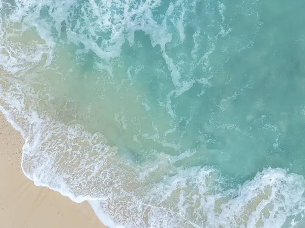 Denizi ve kumsalda dalgaları gösteren bir hava aracıyla çekilmiş hava görüntüsü.