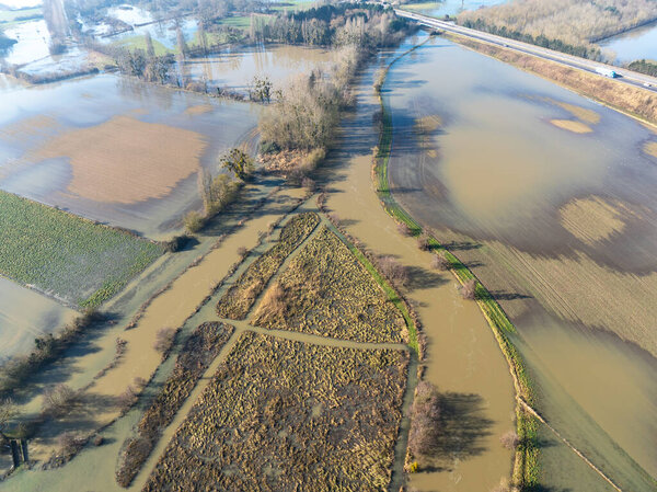 Aerial view taken with a drone showing a flooded river overflowing and a flooded landscape.