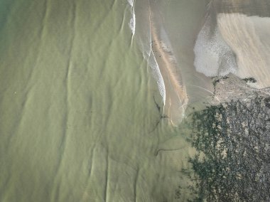 Hava manzaralı, kumlu ve çakıl taşı plajlı bir dron ve mavi ve yeşil deniz. Arkaplan olarak kullanılabilen desenli resim