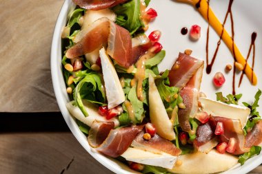 Camembert ve jamonlu salata, roka ve hafif seramik tabakta balzamik ve hardal soslu fındık..