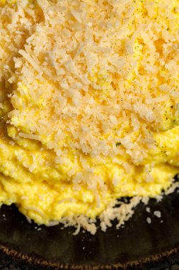 Mısır lapası Mamaliga keçi peyniri ve domuz pastırması parçaları koyu ahşap tahtalar üzerinde geniş kenarlı seramik tabakta..