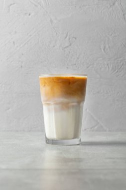 Gri taşlı arka planda şeffaf bir cam bardakta espresso kahveli milkshake..